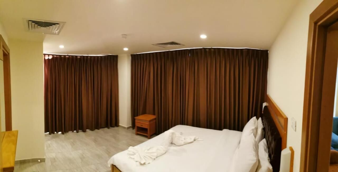 Una habitación de hotel con cama, mesita de noche y una silla de madera.