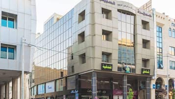 A multi-story building with a modern architectural style, featuring a glass facade and several ground-level retail spaces.