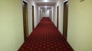 A hotel hallway with a red carpet, doors on both sides, and a ceiling light. - Abu Turan Hotel (Baku)
