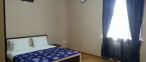 A bedroom with a bed, a clock, and a window with curtains.