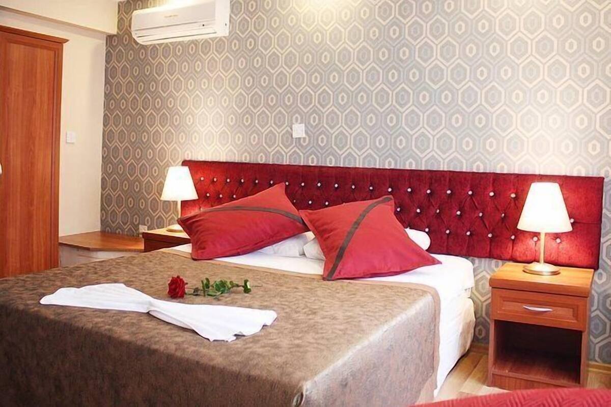 A hotel room with a large bed, two bedside tables, a wardrobe, and a patterned wall.