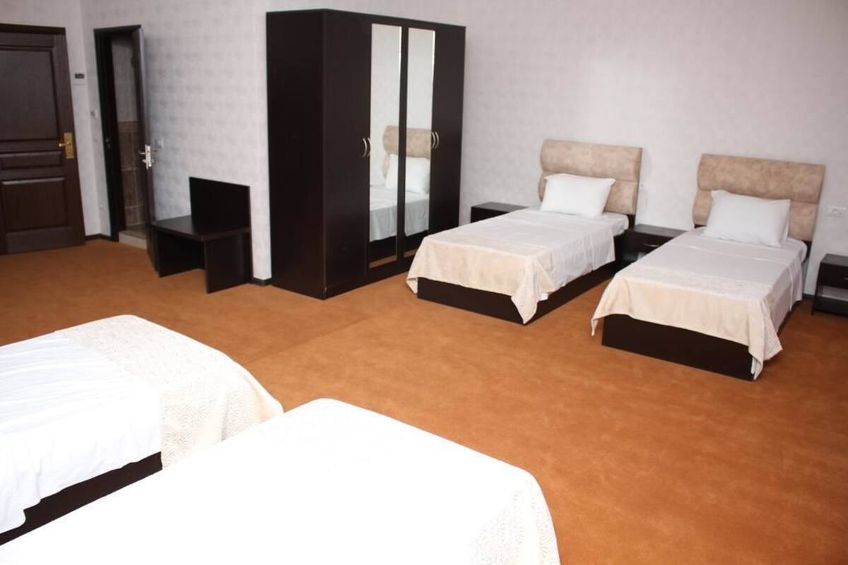 A hotel room with two single beds, a large wardrobe, and a small table.