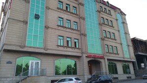 A multi-story building with a large arched entrance and a sign reading "ABU-FUAD HOTEL". - Abu Turan Hotel (Baku)