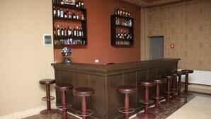 A bar area with a counter and multiple stools. - Abu Turan Hotel (Baku)