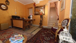 A living room with a wooden coffee table, a red armchair, a white side table with a lamp, a mirror, and a staircase leading to an upper floor. - 40.17 San Marco (Venice)