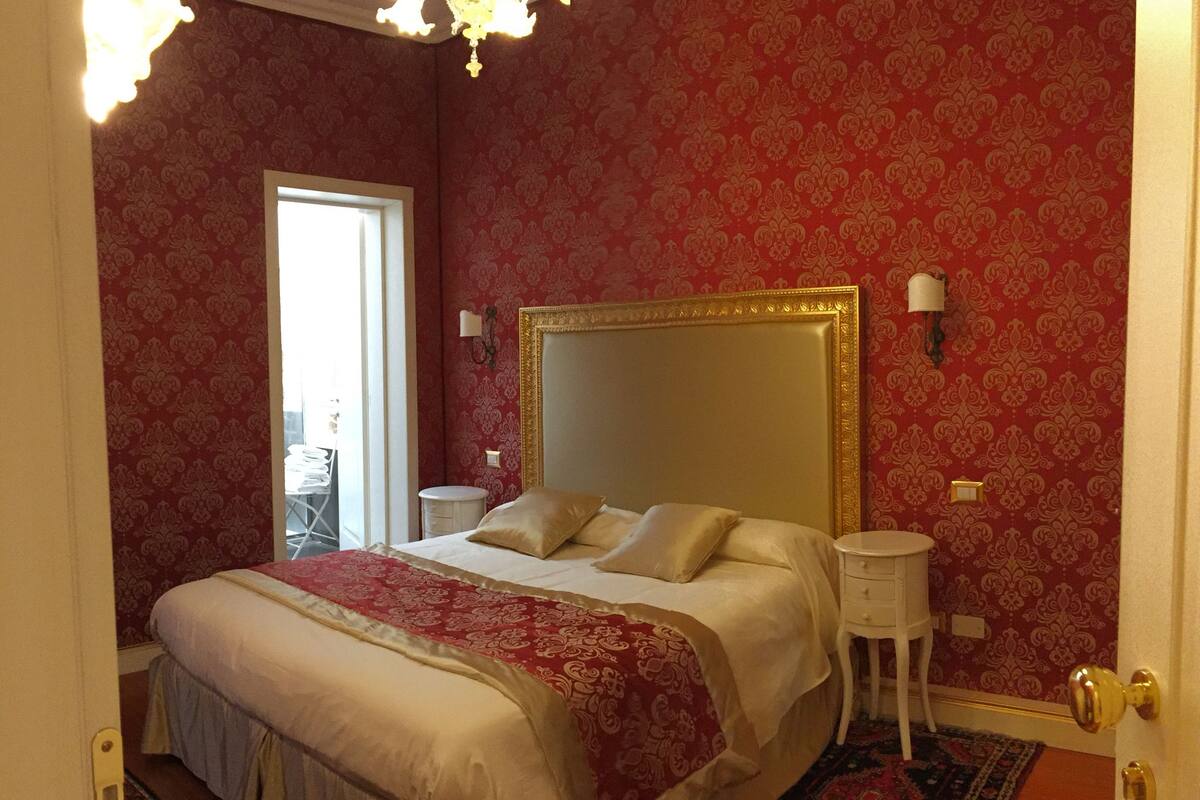 A bedroom with a large bed, a nightstand, a chair, and a door.