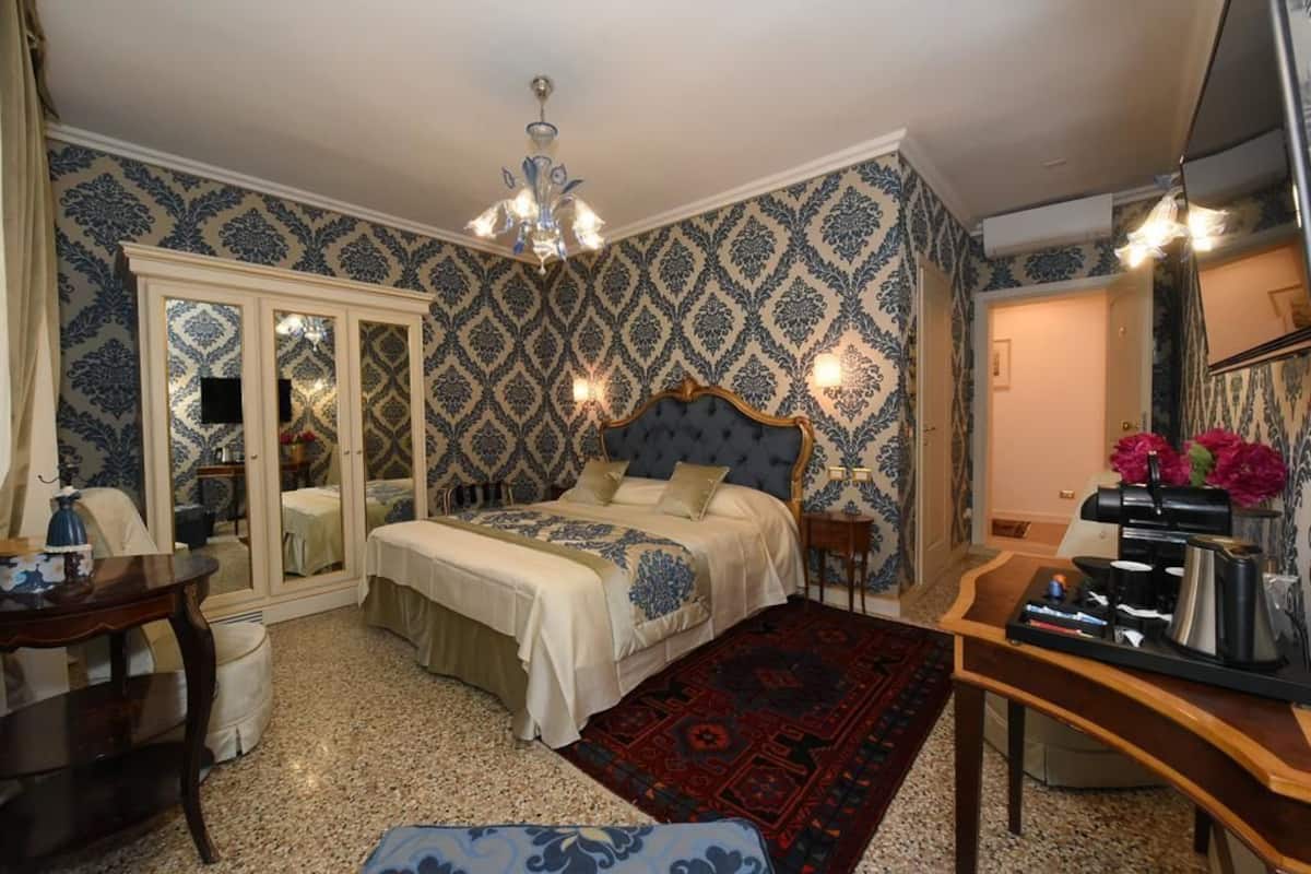 A bedroom with a large bed, a desk, a chair, a dresser, and a mirror.