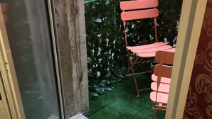 A small outdoor area with a green artificial turf, a pink folding chair, and orange flowers in the background. - 40.17 San Marco (Venice)