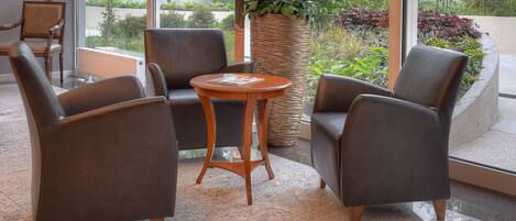 Un área de estar moderna con sillones de cuero, una mesa de madera y una planta grande en maceta.