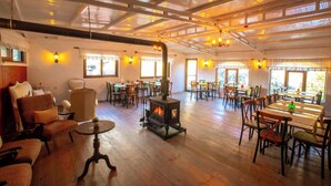 A spacious room with a wood-burning stove, wooden furniture, and large windows allowing natural light. - Sirince Klaseas Hotel & Restaurant (Selçuk)