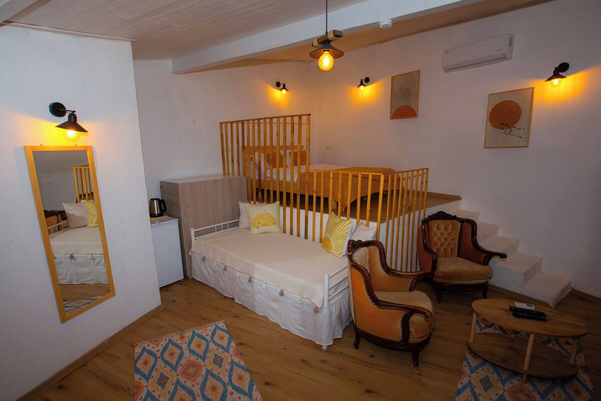 A cozy bedroom with a bunk bed, a wooden chair, a small table, and a mirror on the wall.