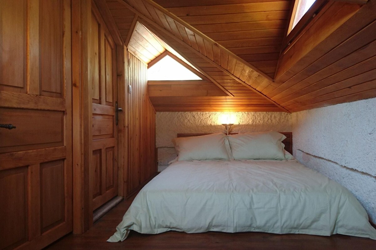 Ein Schlafzimmer mit Holzboden, einem Bett mit weißer Bettwäsche und einem Oberlicht.