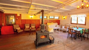A cozy room with a wood-burning stove, wooden walls, and a dining area with chairs and a table. - Sirince Klaseas Hotel & Restaurant (Selçuk)