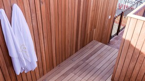 Un jacuzzi en una terraza de madera con toallas colgadas en la pared.