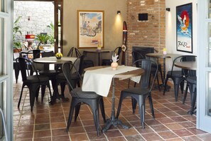 A restaurant with brick walls, tiled flooring, and multiple tables and chairs.
