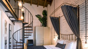 Un dormitorio con cama, armario, escalera de caracol y una planta en maceta.
