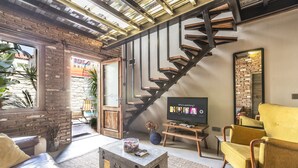 Una sala de estar moderna con una escalera, televisor y asientos cómodos.