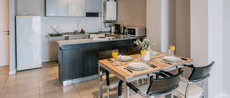 A modern kitchen with white cabinets, a central island, and a dining area with a table set for four.