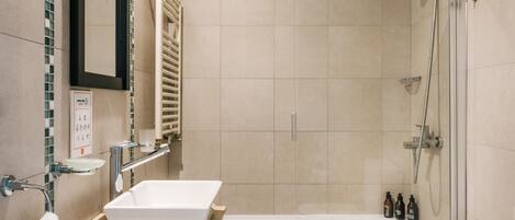 A modern bathroom with a glass-enclosed shower, a white sink, and a bathtub.