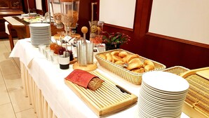 Une table de buffet proposant divers aliments, notamment du pain, des pâtisseries et des condiments.