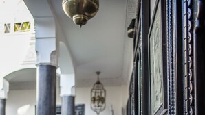 Un pasillo con piso a cuadros, una silla roja y un jarrón rojo.