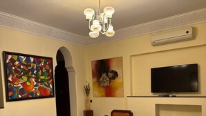 Una sala de estar con un sofá, una mesa de centro, una alfombra, un televisor y obras de arte en las paredes.