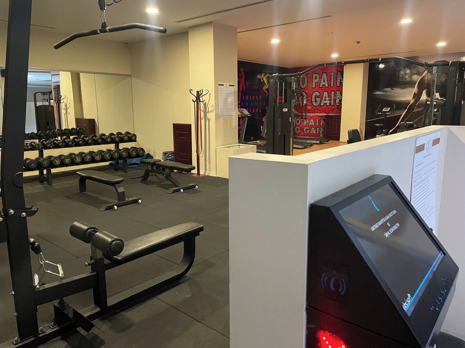 A gym with weightlifting equipment, benches, and dumbbells.