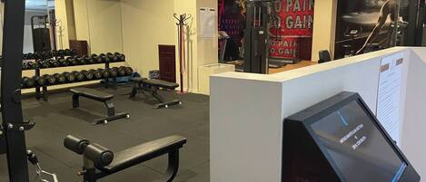 A gym with weightlifting equipment, benches, and dumbbells.