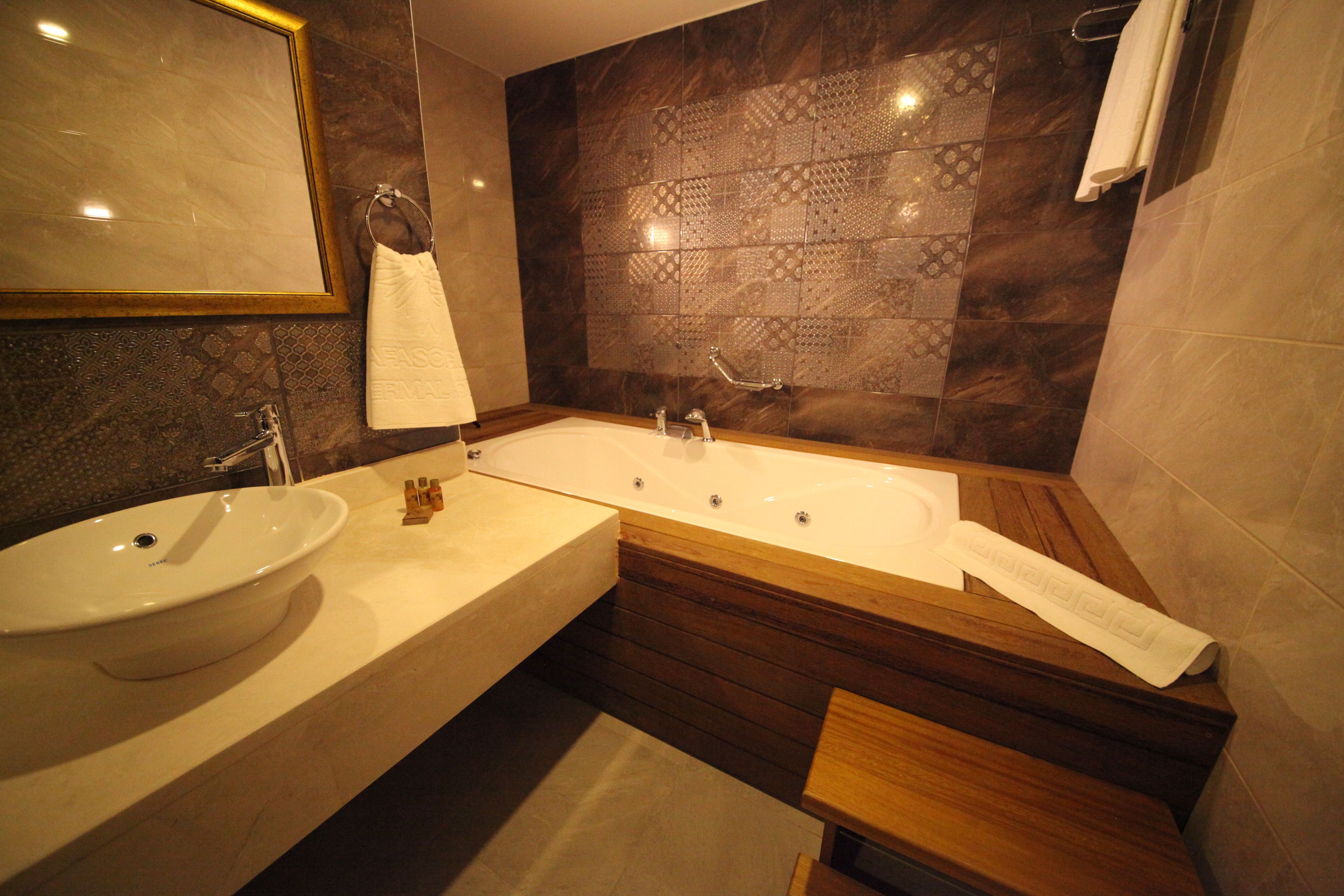 Une salle de bain moderne avec un grand lavabo, une baignoire et un meuble-lavabo en bois.