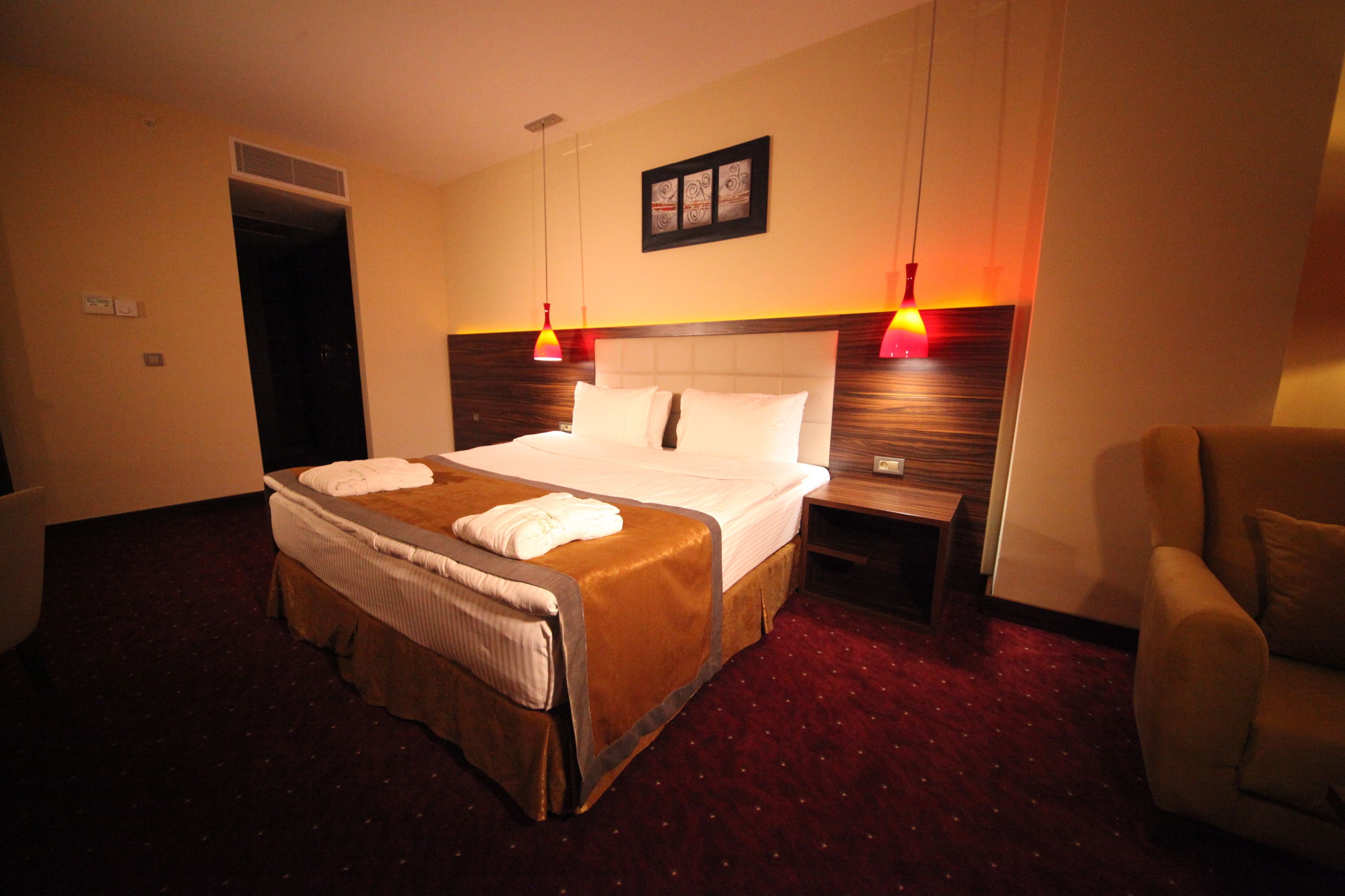 Une chambre d’hôtel avec un grand lit, une table de chevet, une chaise et une porte donnant sur une autre pièce.
