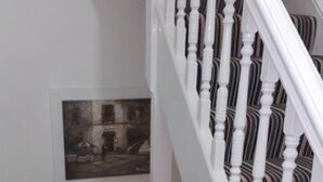 A staircase with white balusters and a striped carpet. - Ali Inn (Oxford)