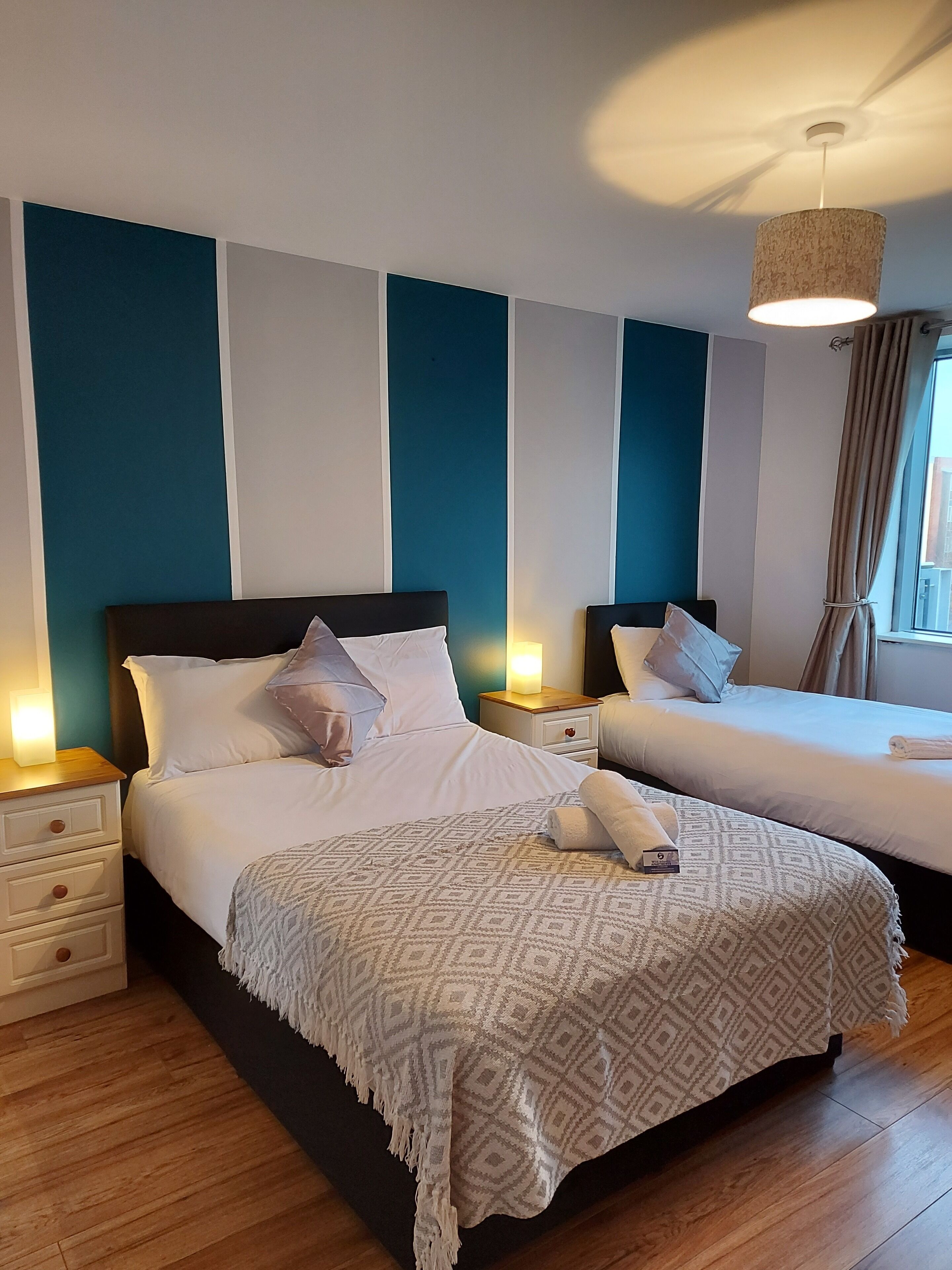 Habitación de hotel con dos camas, suelo de madera y ventilador de techo.