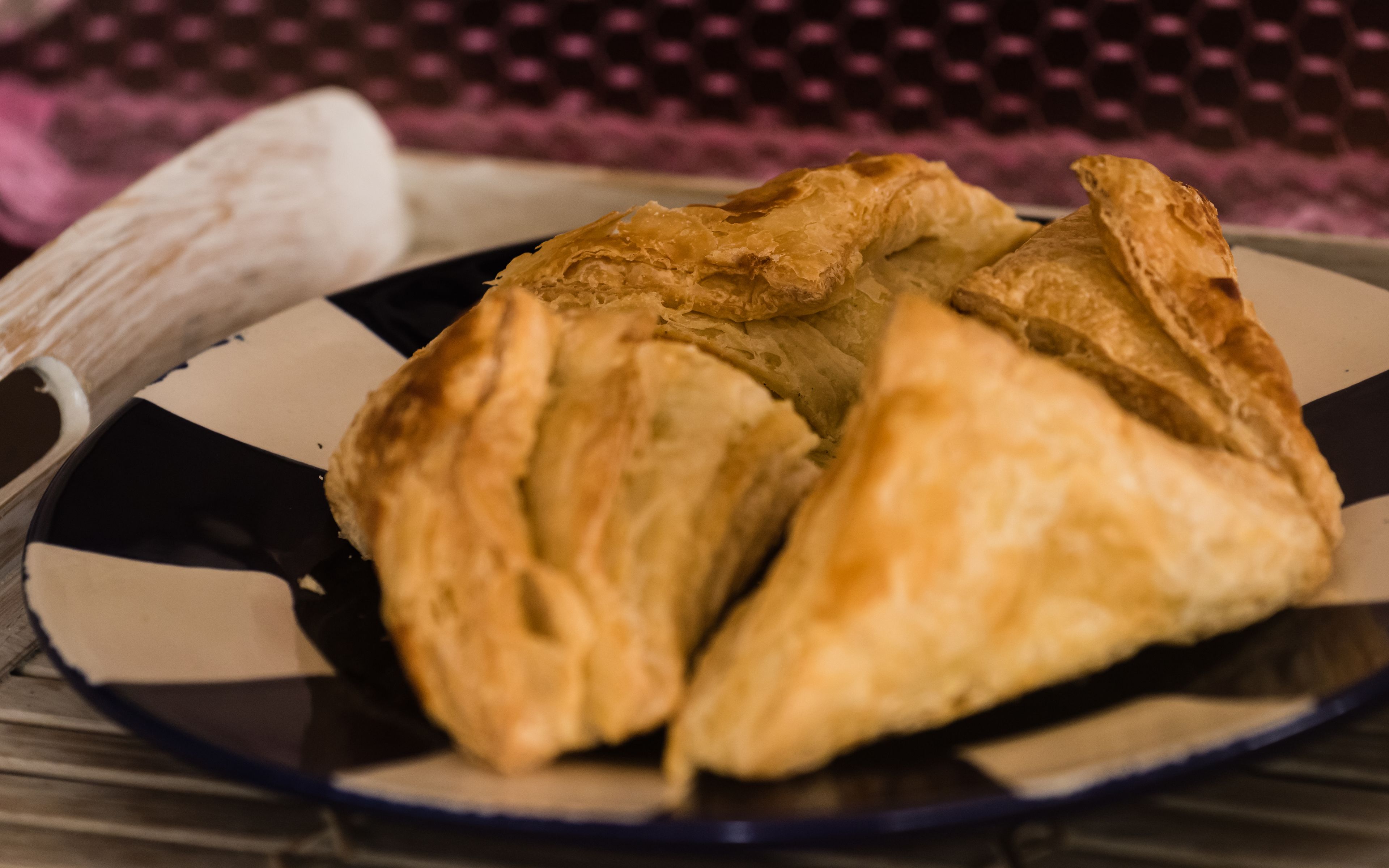 A plate with three triangular pastries on a checkered tablecloth.