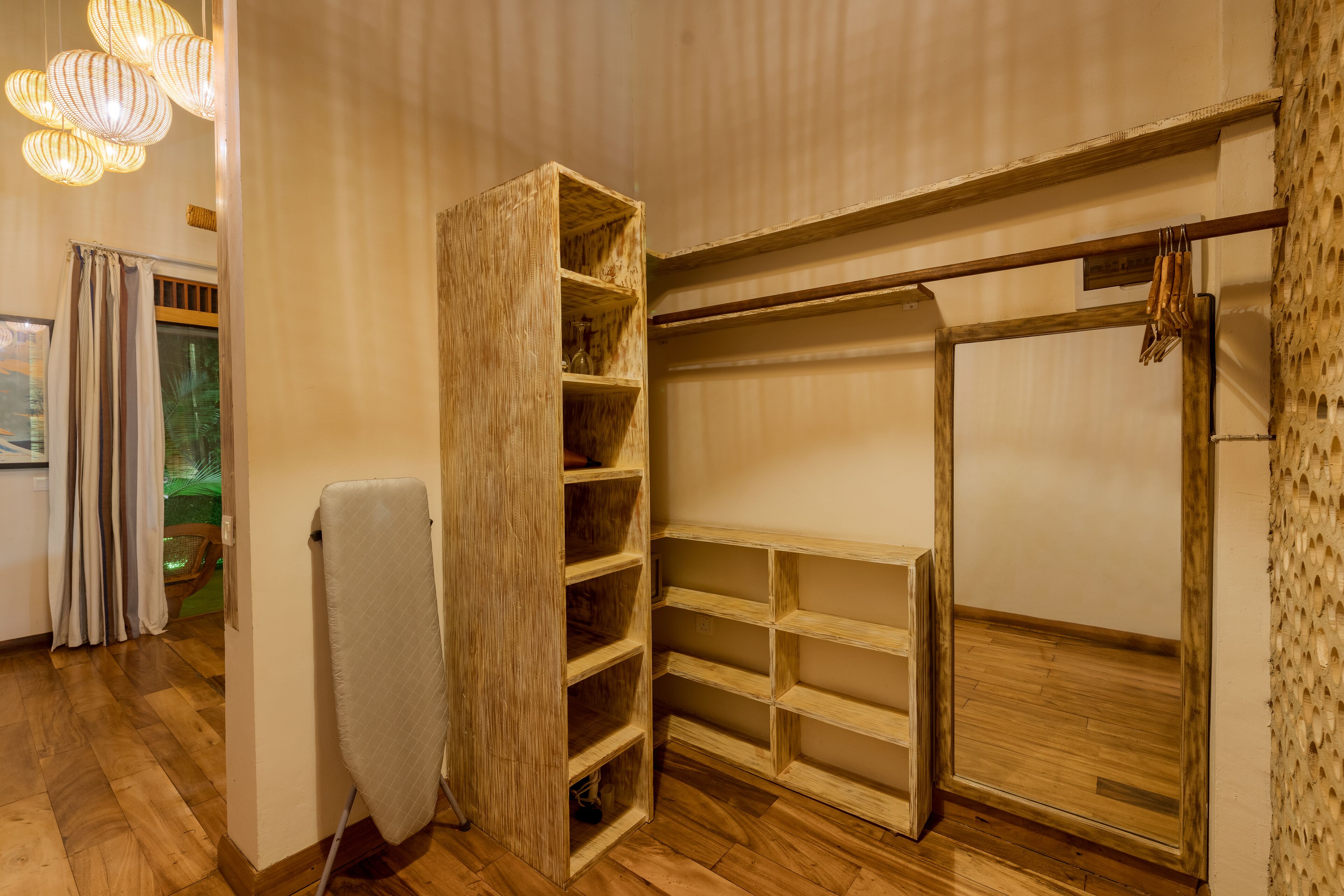 A room with a wooden wardrobe, a drying rack, and a built-in shelving unit.