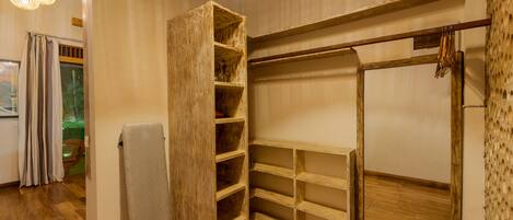 A room with a wooden wardrobe, a drying rack, and a built-in shelving unit.
