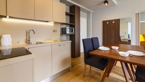 Cozinha moderna com micro-ondas embutido, máquina de café e área de jantar com mesa e cadeiras de madeira.