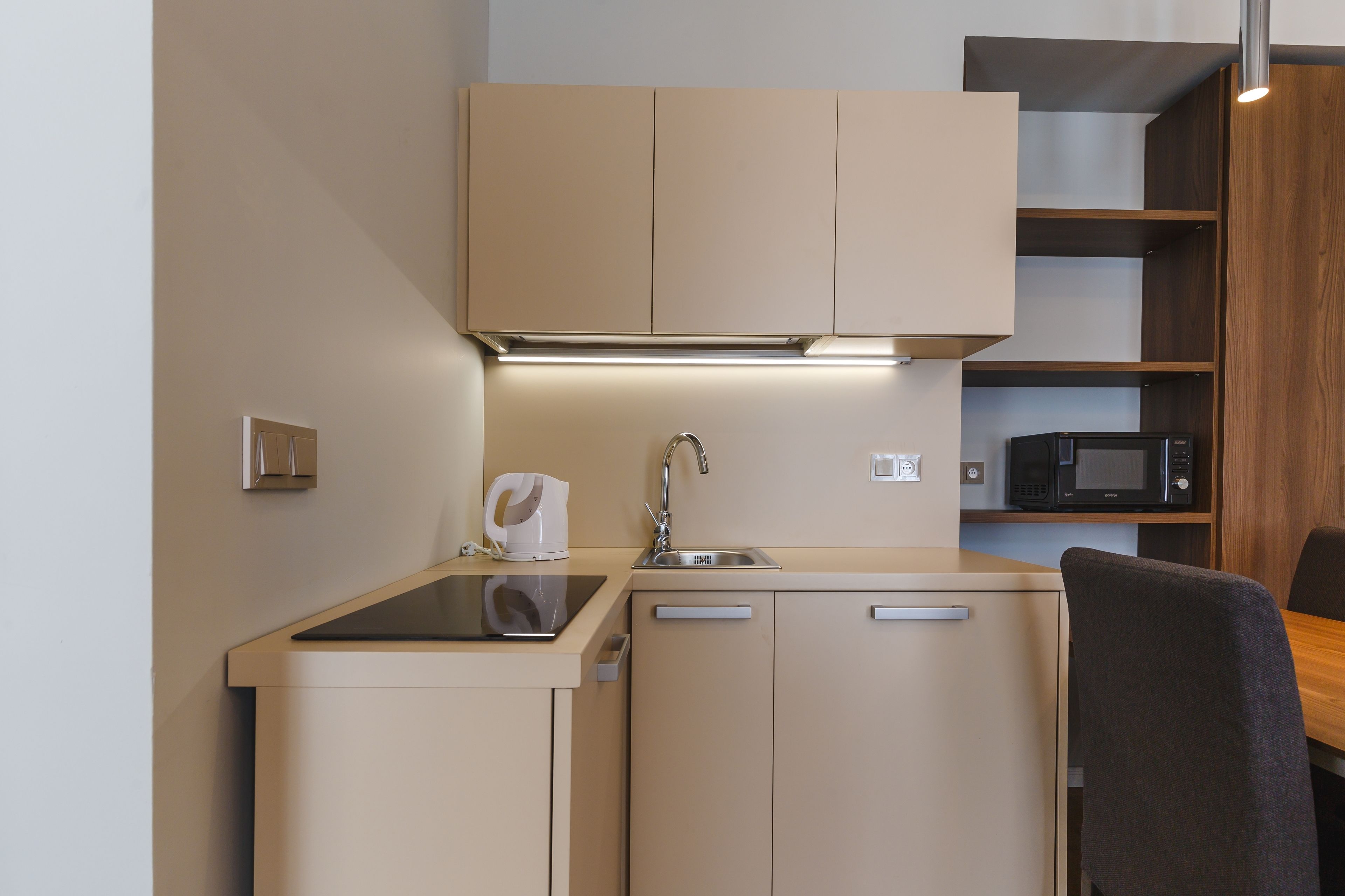 A compact kitchenette with a sink, a microwave, and a small countertop.