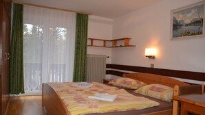 A bedroom with a wooden bed, a desk, a painting on the wall, and a window with curtains. - Apartments Lake Bohinj (Bohinj)