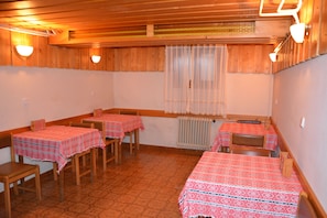 A room with wooden walls, a tiled floor, and tables with red patterned tablecloths. - Apartments Lake Bohinj (Bohinj)