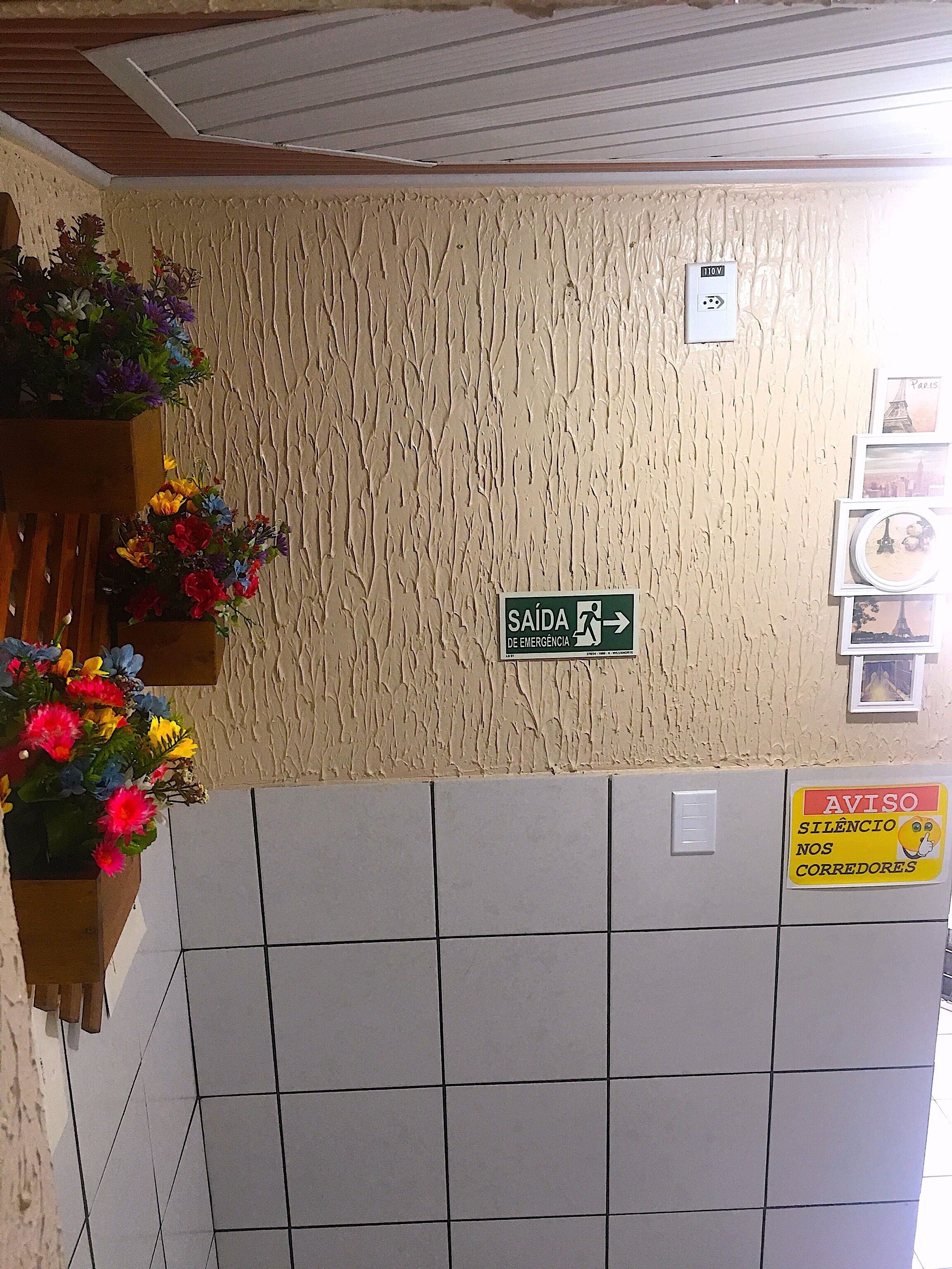 A wall with a textured finish, a sign indicating an emergency exit, and a sign requesting silence from drivers.