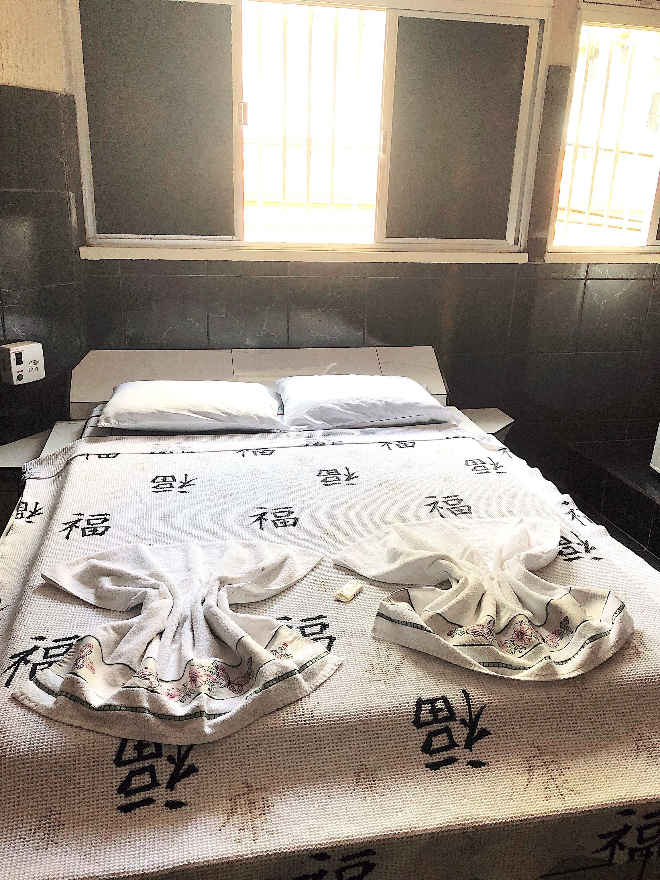 Una habitación con cama, ventana y un calentador fijado a la pared.