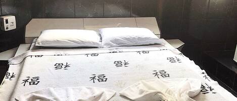 A room with a bed, a window, and a wall-mounted heater.
