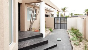 A residential building with a paved entrance, steps leading to a door, and a gated driveway. - Villa West Beach (Cape Town)