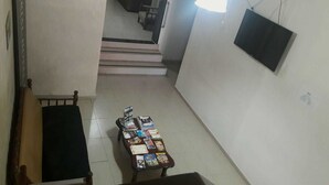 Un pasillo con una mesa que exhibe libros y revistas, un televisor montado en la pared y una escalera que conduce a otra habitación.