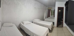 Una habitación con tres camas individuales, una mesita y un armario.