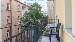 A balcony with a chair, a railing, and a view of adjacent buildings.