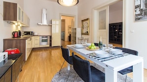 A modern kitchen with a dining area, wooden cabinets, a built-in oven, and a dining table set for four.