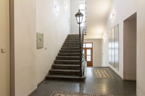 A staircase with a handrail, a patterned rug at the bottom, and a door at the top. - Melnicka Flat (Prague)