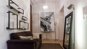 A modern living room with a sofa, a large framed picture of the Eiffel Tower, and a floor lamp.