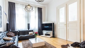 A modern living room with a black leather sofa, a white coffee table, and a flat-screen TV.